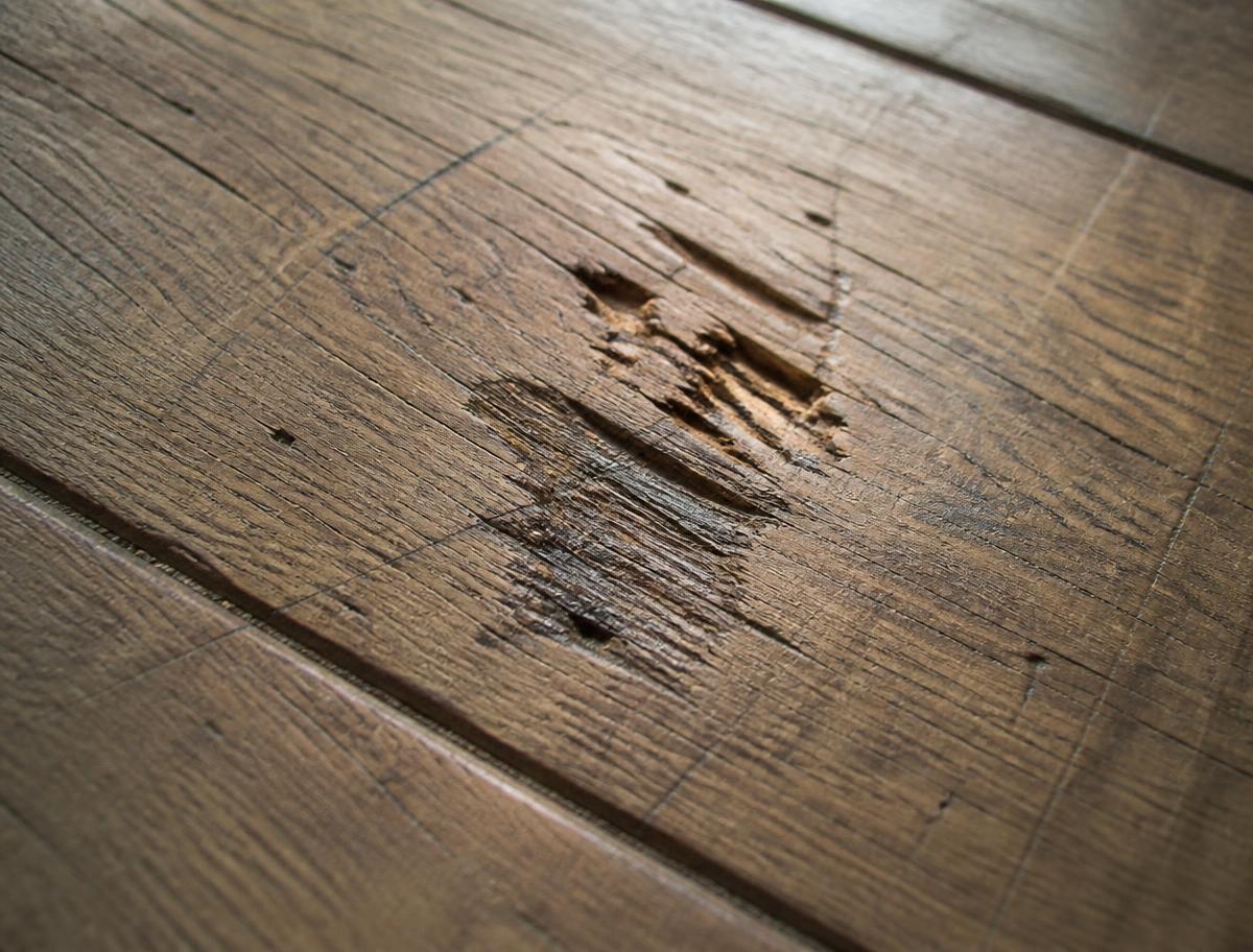 Timber floor with a deep gouge and scratches before repair